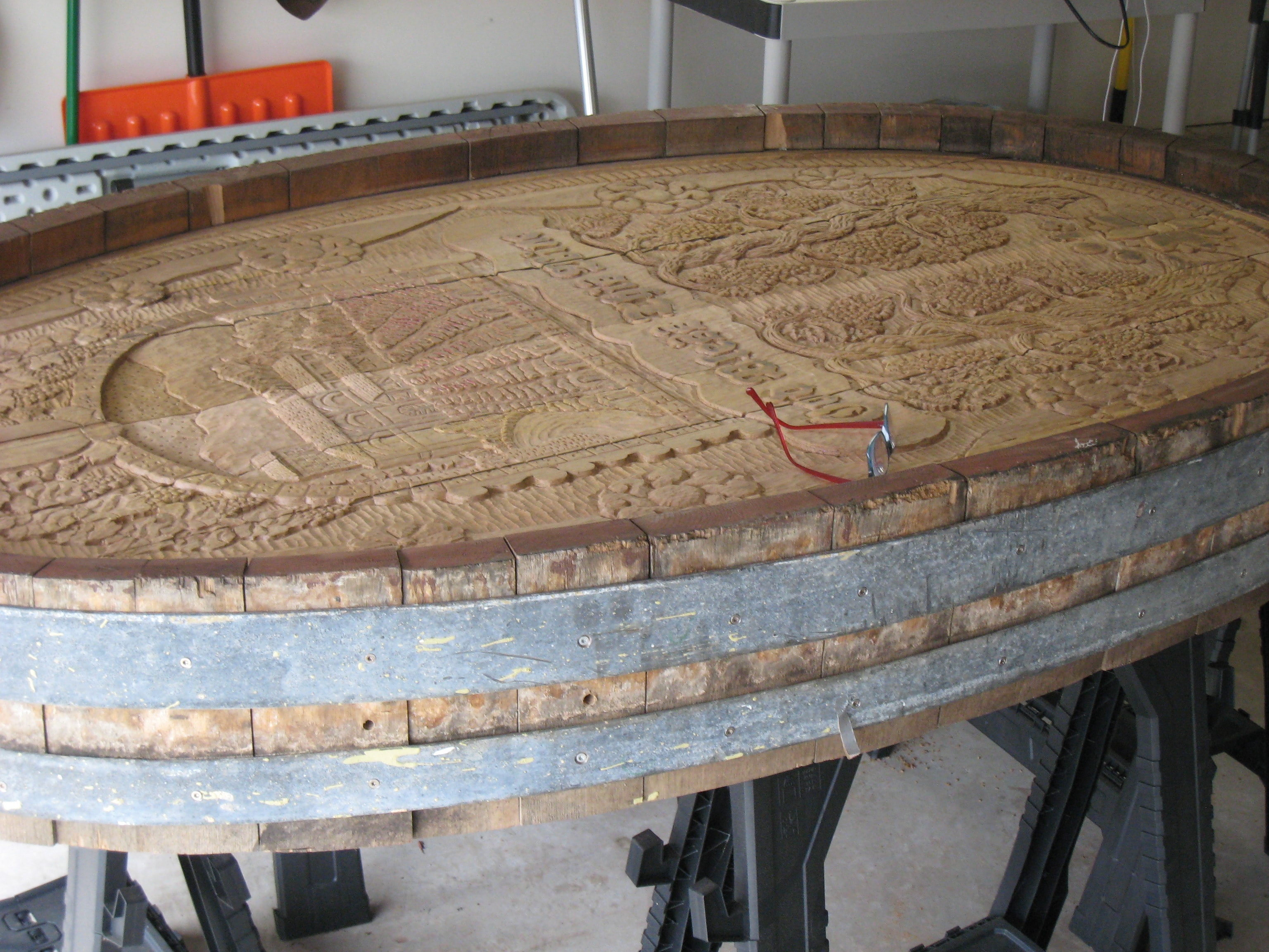 The wine cask end on the carving rack showing the vineyard scene emerging in relief after many weeks of carving